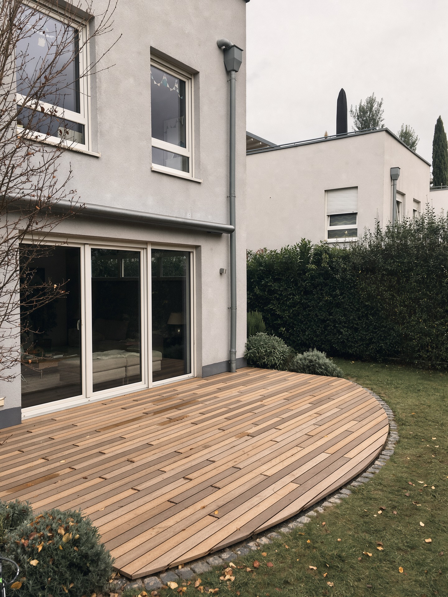 Holzterrasse mit gerundetem Abschluss vor einem Wohnhaus