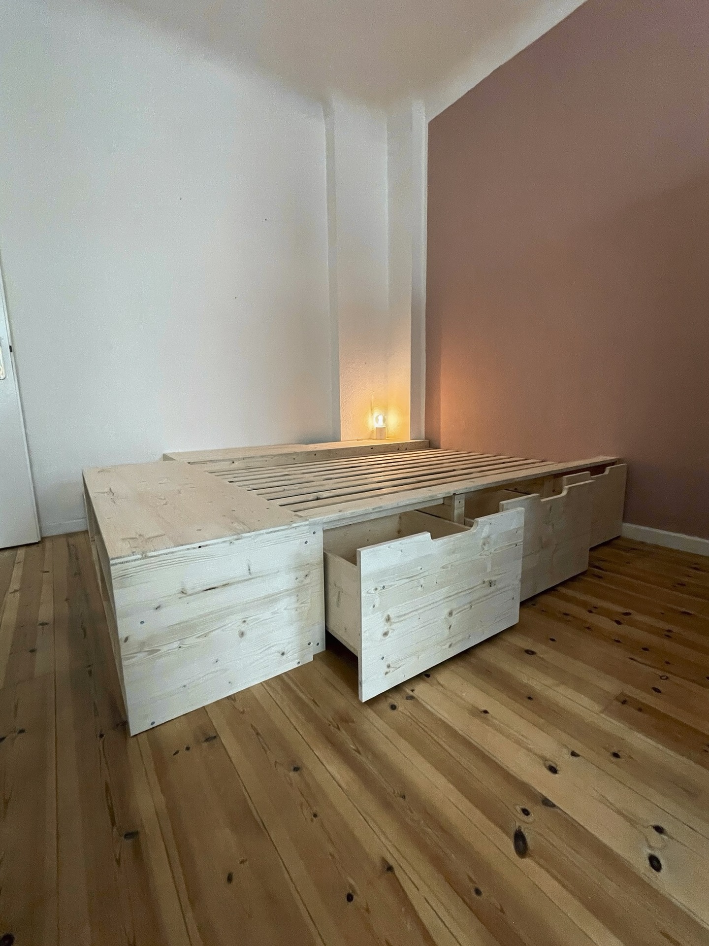 Umgesetztes Holzbett mit drei geöffneten Schubladen